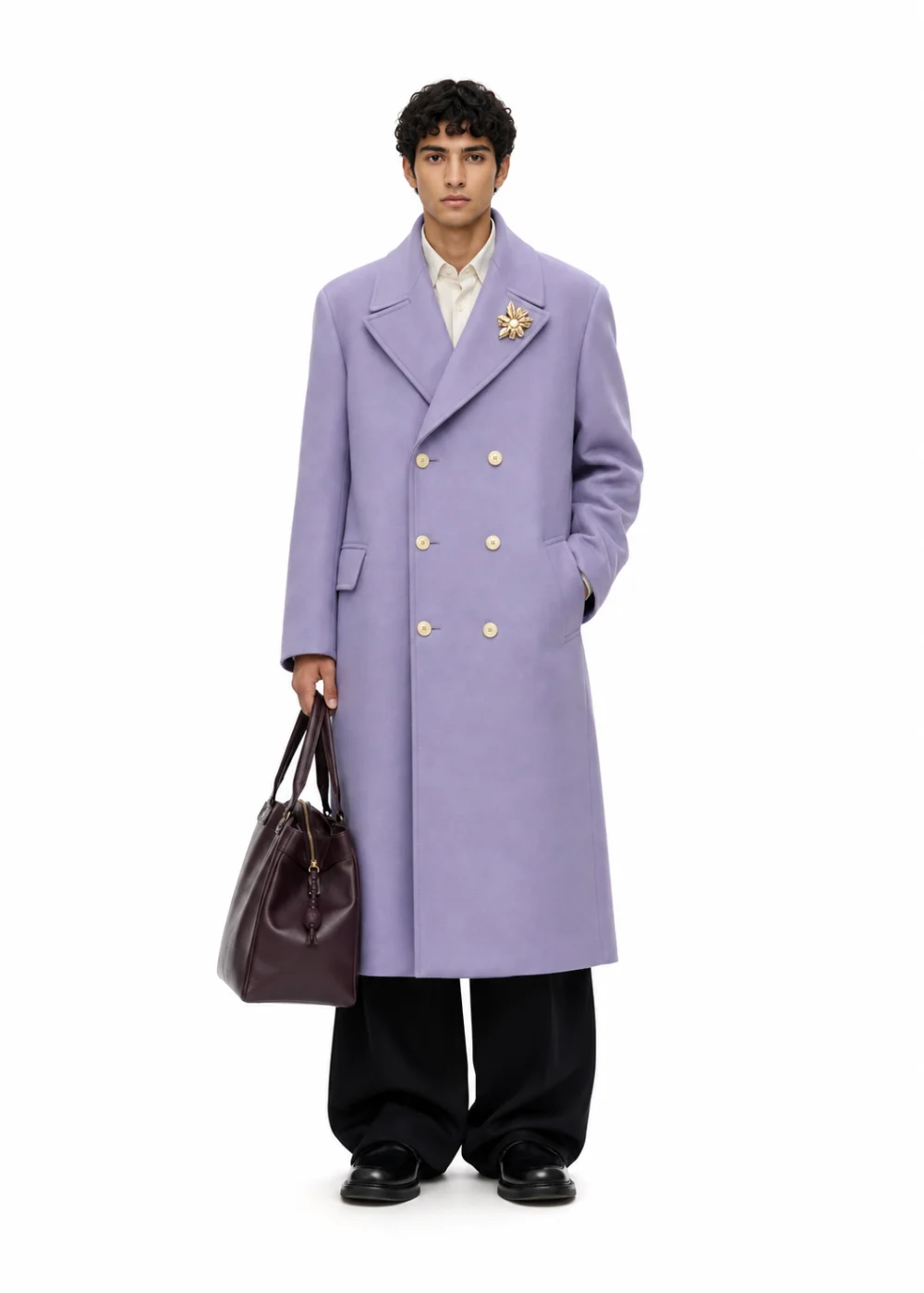 Catalog photo on white of a man in a long lavender double-breasted coat with a gold brooch, black trousers and loafers, holding a dark leather bag.