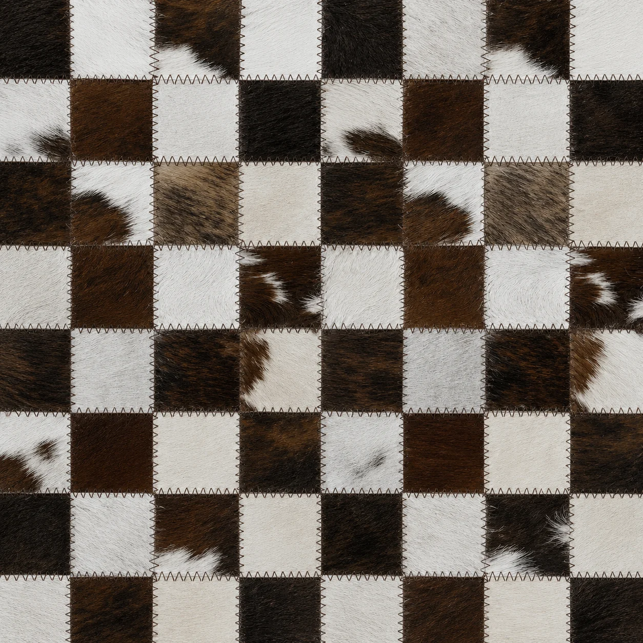 Checkerboard of brown, black and white hair-on cowhide squares stitched together.
